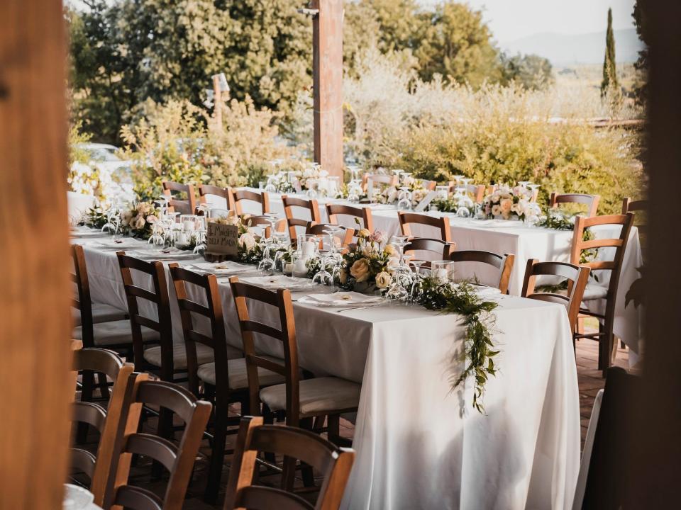 An outdoor wedding venue with two tables with flowers on them.
