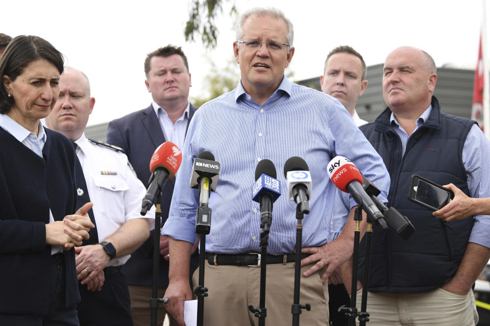 Australia's Prime Minister Scott Morrison, with NSW Premier Gladys Berejiklian, left, speaks to the media during a visit to the Wollondilly Emergency Control Centre in Sydney, Sunday, Dec. 22, 2019. Morrison on Sunday apologized for taking a family vacation in Hawaii as deadly bushfires raged across several states, destroying homes and claiming the lives of two volunteer firefighters. (Joel Carrett/AAP Images via AP)