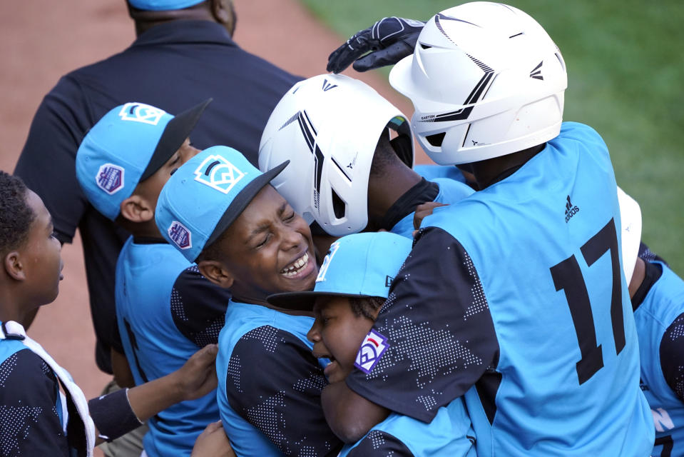 Curacao's Jaydion Louisa, center, is mobbed by his teammates on the way back to the dugout after driving in two runs with a base hit against Mexico during the fifth inning of a baseball game at the Little League World Series tournament in South Williamsport, Pa., Thursday, Aug. 25, 2022. (AP Photo/Tom E. Puskar)