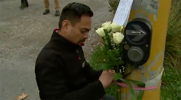 A man places flowers at the intersection. Source: 7 News