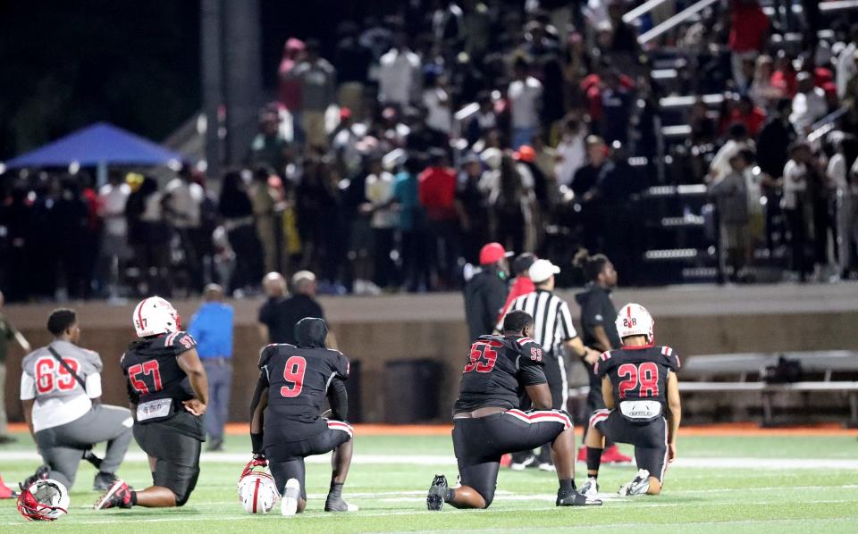 Jenkins players take a knee on the field as Savannah Police work to restore order in the stands on the Jenkins side after a fight in the stands on Friday, August 18, 2023 at Memorial Stadium.