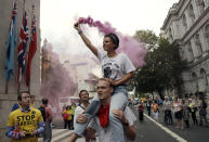 Anti-Brexit supporters carry a flare near the Cenotaph in central London, Wednesday, Aug. 28, 2019. British Prime Minister Boris Johnson asked Queen Elizabeth II on Wednesday to suspend Parliament, throwing down the gauntlet to his critics and causing outrage among opposition leaders who will have even less time to thwart a no-deal Brexit. (AP Photo/Matt Dunham)