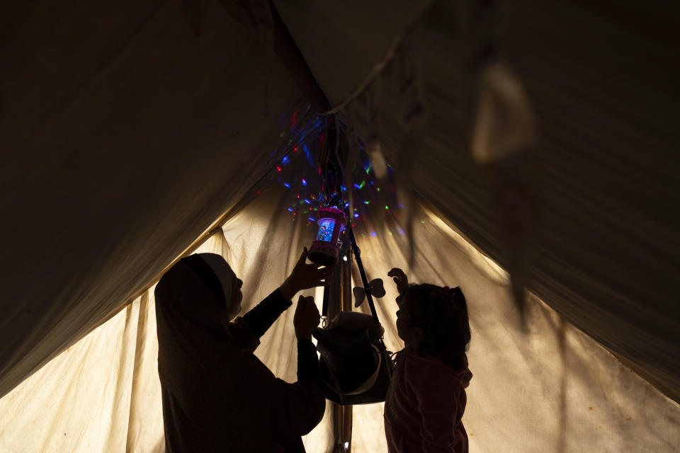 Randa Baker, desplazada por el bombardeo israelí sobre la Franja de Gaza, cuelga decoraciones y luces del Ramadán con su hija en el inicio del mes sagrado musulmán, en un campamento improvisado en la zona de Muwasi, en el sur de Gaza, el 11 de marzo de 2024. (AP Foto/Fatima Shbair)