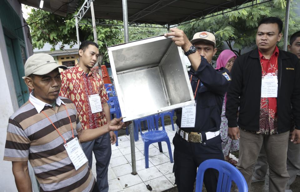 Electoral workers show an empty box before the opening station for voters during the gubernatorial election in Jakarta, Indonesia, Wednesday, Feb. 15, 2017. Voting began in the election for governor of the Indonesian capital after a months-long campaign in which the monumental problems facing Jakarta took a backseat to religious intolerance and racial bigotry. (AP Photo/ Achmad Ibrahim)