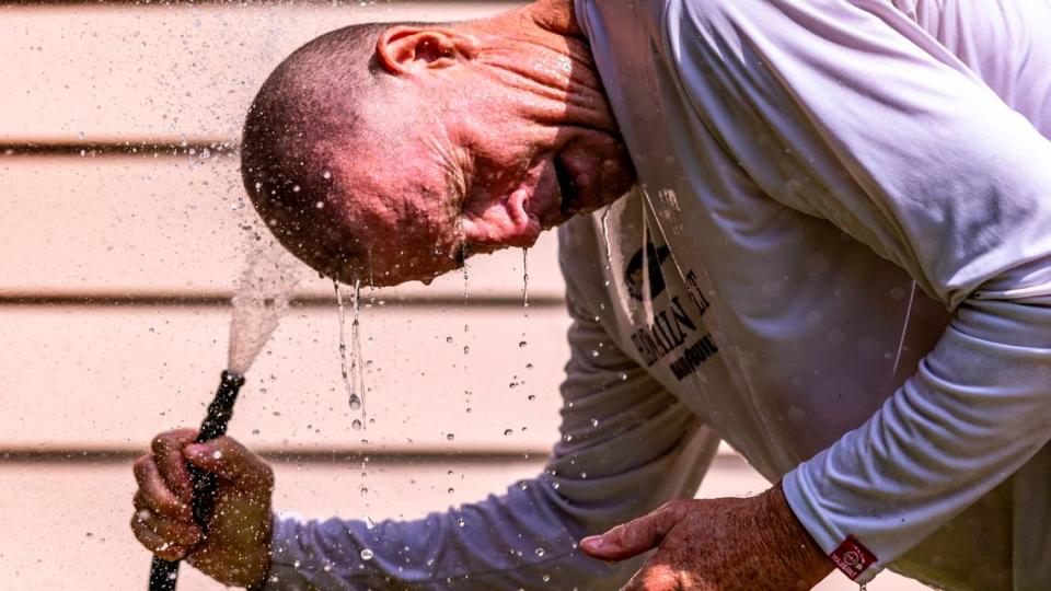 Andy Gilbert cools down with a garden hose after mowing a neighbor’s downtown Raleigh lawn Friday, Aug 25, 2023. Durham, Johnston and Wake counties all reported rates of heat-related EMS calls per 100,000 people at least double the national average of 1.2. Travis Long/tlong@newsobserver.com