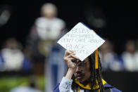 A graduate holds a cap that reads "Biden and Harris don't care about Black people" as President Joe Biden, background left, speaks at Howard University's commencement in Washington, Saturday, May 13, 2023. (AP Photo/Alex Brandon)