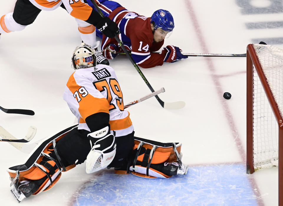 Montreal Canadiens center Nick Suzuki (14) fails to connect with the puck as Philadelphia Flyers goaltender Carter Hart (79) defends the net during the second period of Game 3 of an NHL hockey playoff first-round series Sunday, Aug. 16, 2020, in Toronto. (Frank Gunn/The Canadian Press via AP)