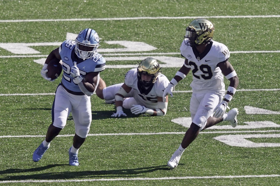 FILE - In this Nov. 14, 2020, file photo, North Carolina running back Javonte Williams (25) runs while Wake Forest defensive back Caelen Carson (29) chases during the first half of an NCAA college football game in Chapel Hill, N.C. The Denver Broncos traded up in the second round of the NFL draft Friday, April 30, 2021, to grab Williams with the 35th overall pick. (AP Photo/Gerry Broome, File)