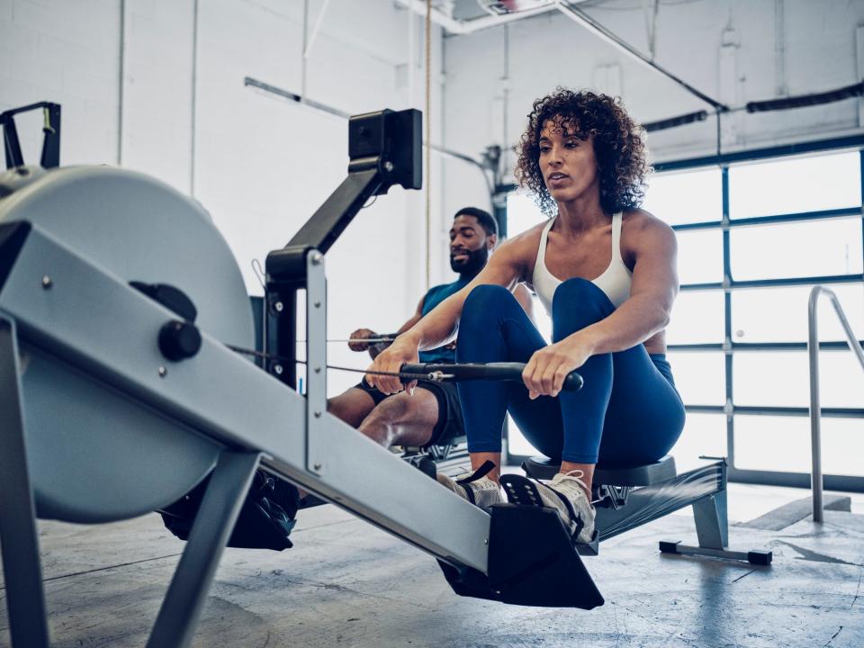 Two athletes in a gym performing a workout on the rower