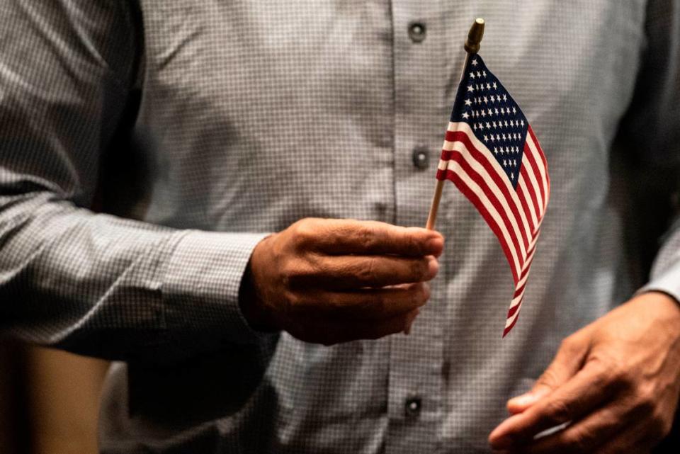 A newly naturalized American citizen holds an American flag during a naturalization ceremony at Dan M. Russell Courthouse in Gulfport on Thursday, Oct. 19, 2023.
