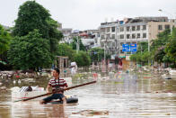 <p>A man uses an improvised flotation device to move through floodwaters on a flooded street in Liuzhou, Guangxi province, China, July 3, 2017. (Photo: STR/AFP/Getty Images) </p>