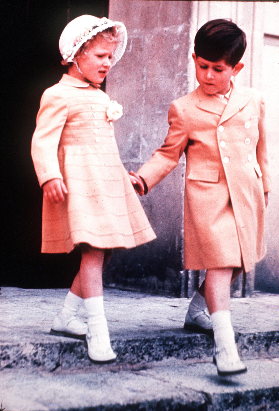 Prince Charles, helps Princess Anne, the Princess Royal down the stairs in Windsor, in 1960. (Getty Images)