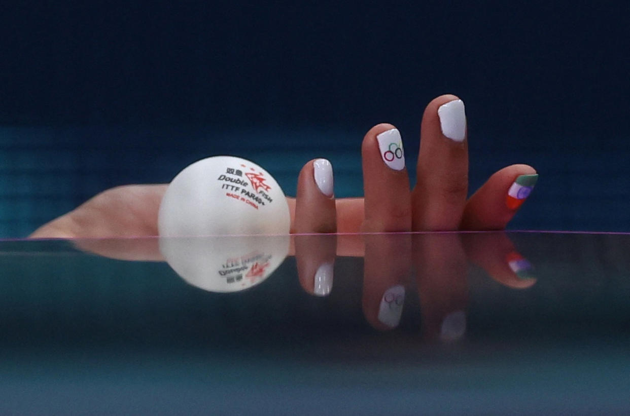 The manicured hand of Manika Batra of India holding a ball during a women's singles table tennis match.