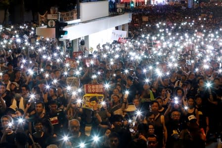 Anti-extradition bill protesters use the flashlights from their phones as they march during the anniversary of Hong Kong's handover to China in Hong Kong