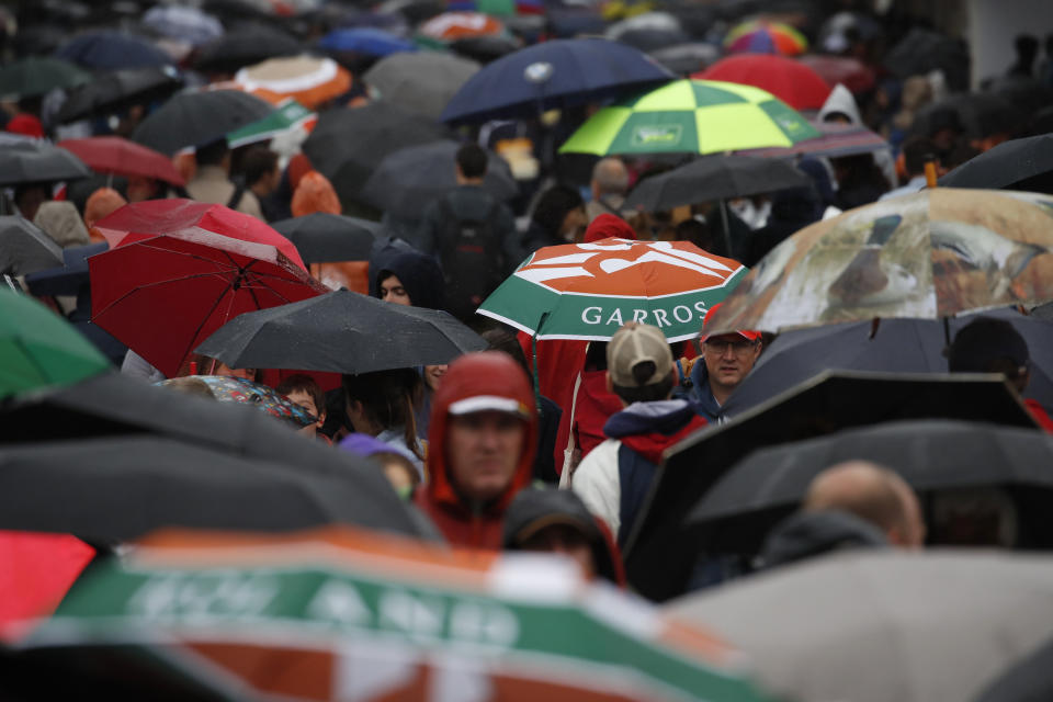 Spectators with umbrellas stroll as rain delayed the start of quarterfinal matches of the French Open tennis tournament at the Roland Garros stadium in Paris, Wednesday, June 5, 2019. (AP Photo/Christophe Ena)
