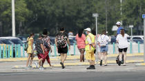 An attendant, front, directs park guests to the entrance of the Magic Kingdom during the reopening at Walt Disney World, Saturday, July 11, 2020, in Lake Buena Vista, Fla. (AP Photo/John Raoux)