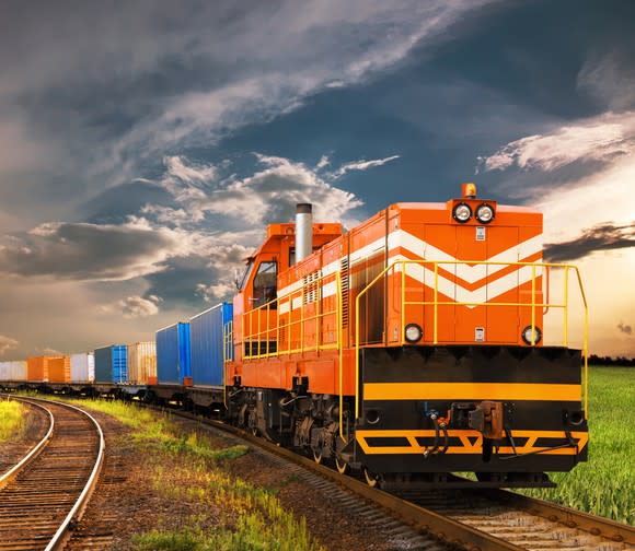 A freight train moving on railroad tracks under a cloudy sky.