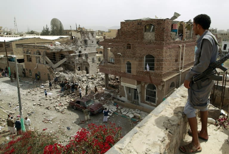 A Huthi militant watches as people inspect the debris of a house destroyed in an air-strike by the Saudi-led coalition, in Sanaa on July 3, 2015