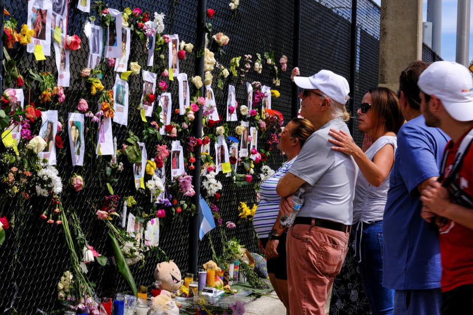 People mourn at the memorial site created by neighbors in front of the partially collapsed building where the rescue personnel continue their search for victims in Surfside, Fla., on June 26, 2021. (Maria Alejandra Cardona / Reuters)