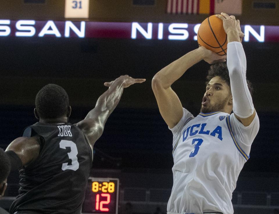 UCLA's Johnny Juzang, right, shoots over Long Beach State's Drew Cobb during the second half Monday.