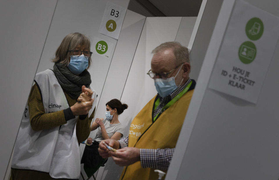 FILE - In this Friday, Feb. 19, 2021 file photo, A logistics officer, right, and a vaccinator, left, prepare to administer an injection of the AstraZeneca coronavirus vaccine to a woman at the Vaccine Village in Antwerp, Belgium. The government on Monday, Feb. 22, 2021 presented scientific projections of the spread of the COVID-19 pandemic in Belgium, indicating it would be very risky to extensively loosen the current restrictions over the coming weeks. (AP Photo/Virginia Mayo, File)