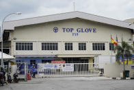 Workers from Top Glove walk out fromTop Glove factory in Shah Alam, Malaysia, Wednesday, Nov. 25, 2020. Malaysia's Top Glove Corp., the world's largest maker of rubber gloves, says it expects a two to four-week delay in deliveries after more than 2,000 workers at its factories were infected by the coronavirus, raising the possibility of supply disruptions during the pandemic. (AP Photo/Vincent Thian)