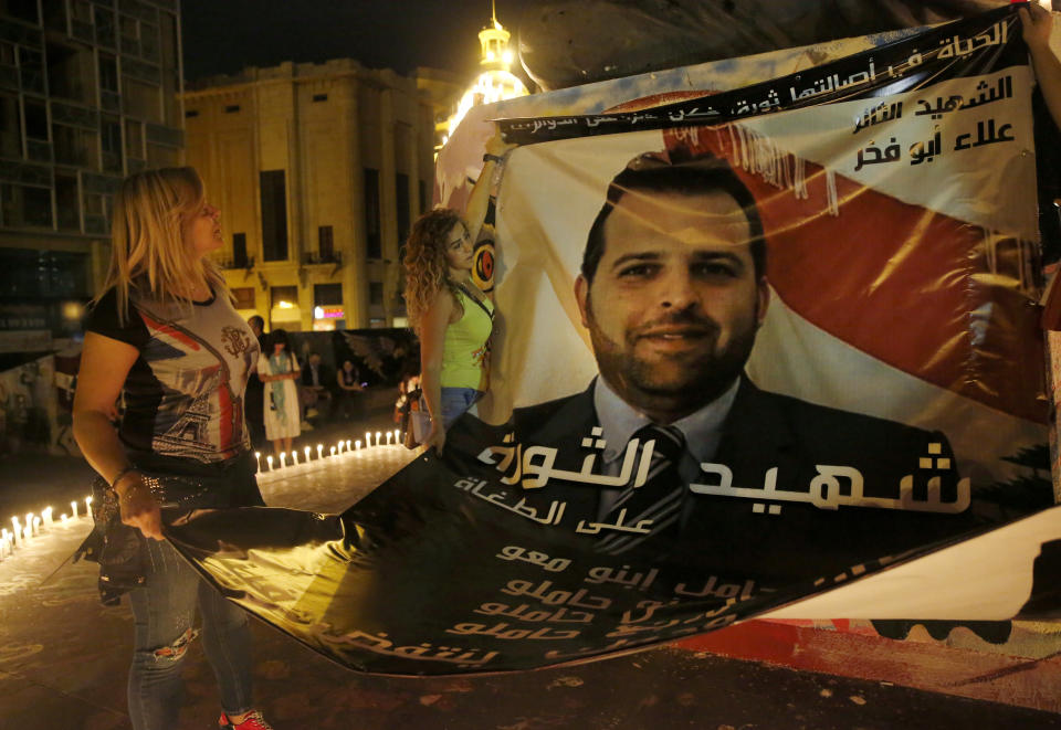Anti-government protesters hang a giant portrait for Alaa Abu Fakher, who was killed by a Lebanese soldier during Tuesday night protests south of Beirut, at the Martyr square, in downtown Beirut, Lebanon, Wednesday, Nov. 13, 2019. (AP Photo/Hussein Malla)
