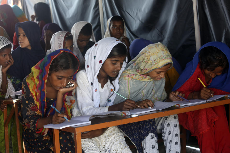 Flood affected children attend school organized by Islamic group Jamaat-e-Islami Pakistan, in Sukkur, Pakistan, Sunday, Sept. 4, 2022. Officials warned Sunday that more flooding was expected as Lake Manchar in southern Pakistan swelled from monsoon rains that began in mid-June and have killed nearly 1,300 people. (AP Photo/Fareed Khan)