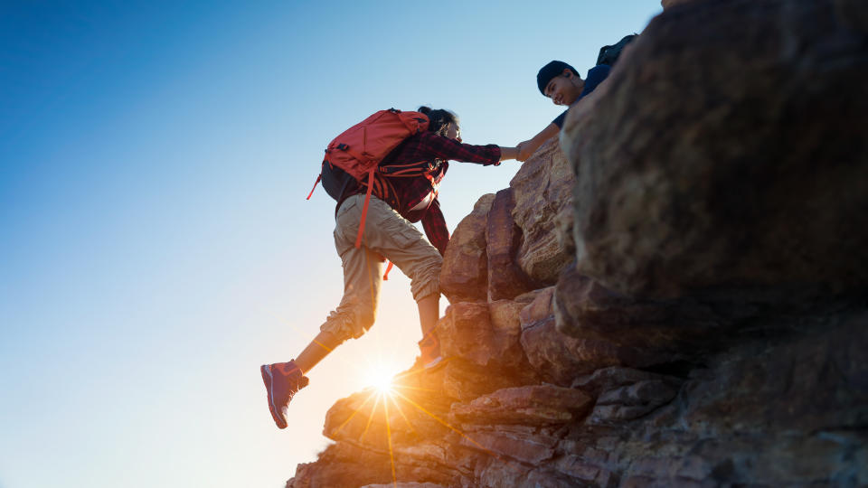 Young asian couple climbing up on the mountain,hiking and team work concept.