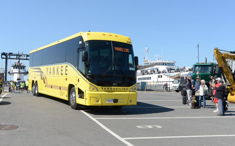 Bystanders cheer as a bus carrying migrants from Martha's Vineyard to Joint Base Cape Cod leaves the Woods Hole, Martha's Vineyard and Nantucket Steamship Authority terminal on Friday morning.