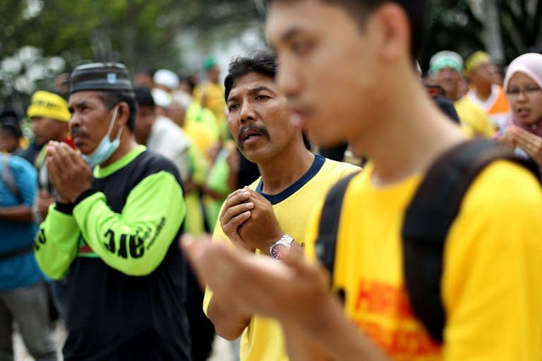 Protesters offer prayers outside the national mosque as they take part in an opposition rally ahead of upcoming elections, in Kuala Lumpur, on January 12, 2013. Malaysian opposition supporters gathered by the thousands in the capital to call for the ouster of the country's long-ruling government in elections due within months