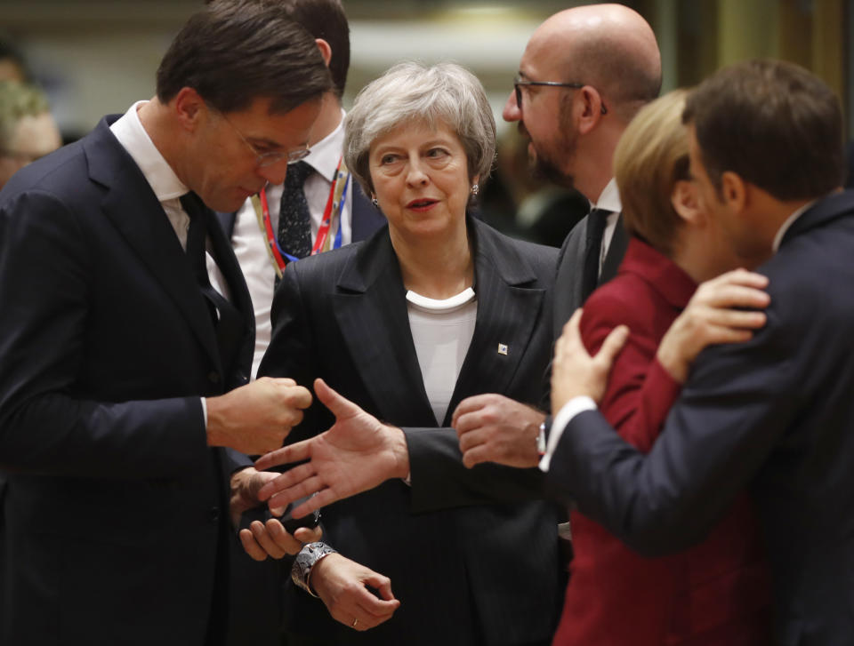 British Prime Minister Theresa May, center, arrives for a round table meeting at an EU summit in Brussels, Thursday, Dec. 13, 2018. EU leaders gathered Thursday for a two-day summit which will center on the Brexit negotiations. At right is French President Emmanuel Macron greeting German Chancellor Angela Merkel. (AP Photo/Alastair Grant)