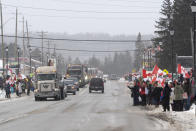 Protesters and supporters against a COVID-19 vaccine mandate for cross-border truckers cheer as a parade of trucks and vehicles pass through Kakabeka Falls outside of Thunder Bay, Ontario, on Wednesday, Jan. 26, 2022. (David Jackson/The Canadian Press via AP)