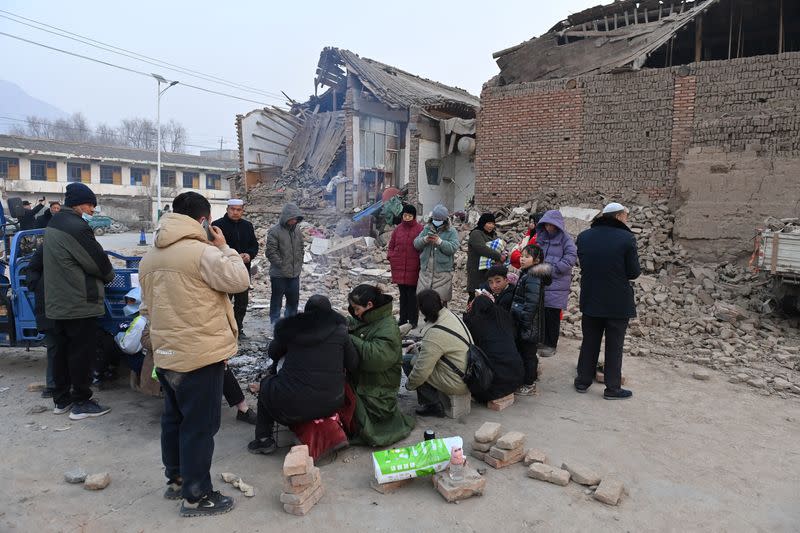 Los residentes se calientan junto a un fuego al lado de los edificios dañados en la ciudad de Dahejia tras el terremoto en el condado de Jishishan, provincia de Gansu, China