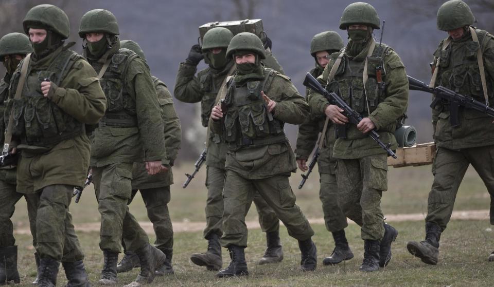 A pro-Russian soldier flashes a victory sign while marching near a Ukrainian army base in Perevalne, Crimea, Wednesday, March 19, 2014. Crimea's self-defense forces on Wednesday stormed the Ukrainian navy headquarters in the Black Sea port of Sevastopol, taking possession without resistance a day after Russia signed a treaty with local authorities to annex the region.(AP Photo/Vadim Ghirda)