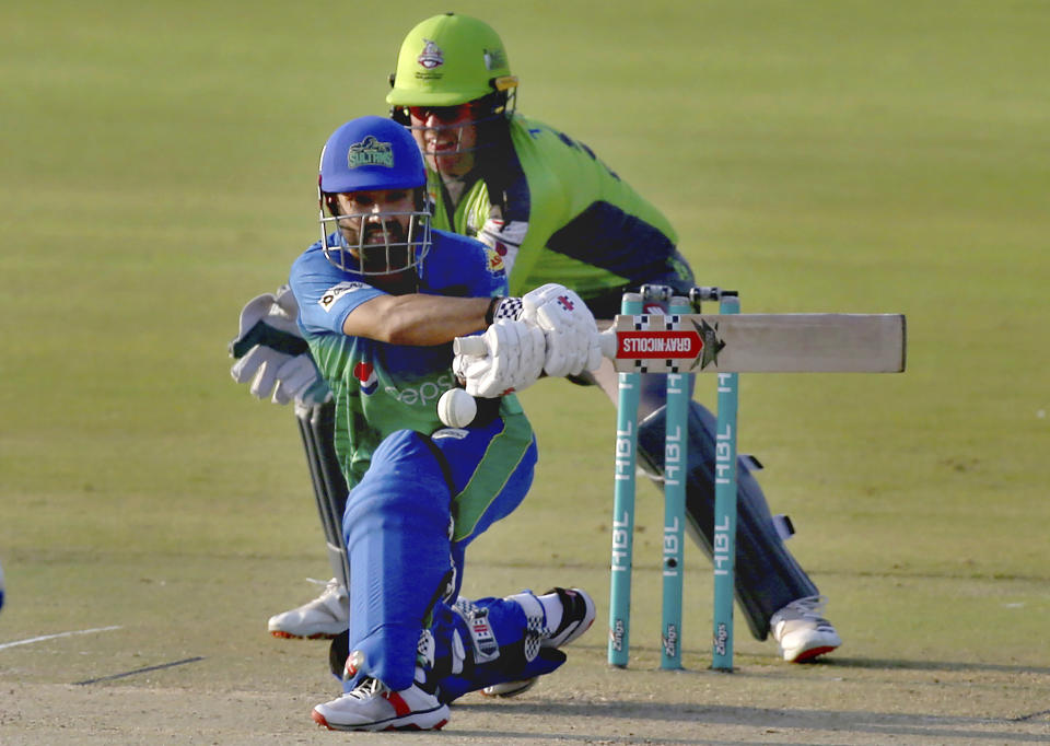 Multan Sultans' Mohammad Rizwan, front, plays a shot while Lahore Qalandars' Ben Dunk watches during a Pakistan Super League T20 cricket match between Lahore Qalandars and Multan Sultans at the National Stadium, in Karachi, Pakistan, Friday, Feb. 26, 2021. (AP Photo/Fareed Khan)