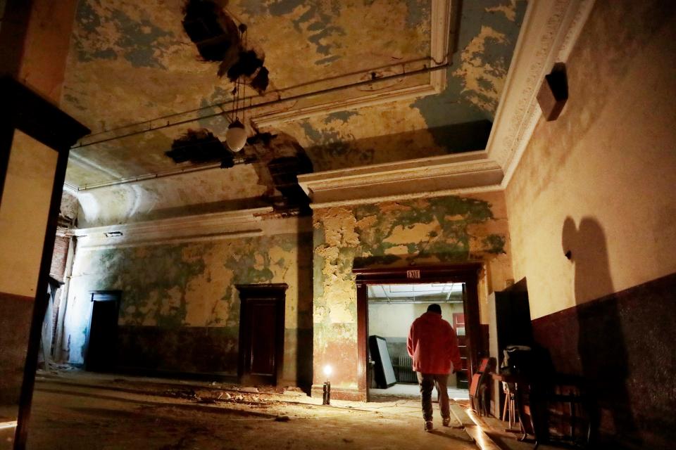 A worker places some dishes onto a pile on the side of the corridor of the old Orpheum theater in New Bedford, MA.