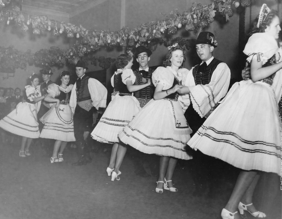 Clusters of grapes hang from the ceiling as Hungarian American dancers perform at the 1940 grape festival at the Magyar Home on East Thornton Street in Akron.