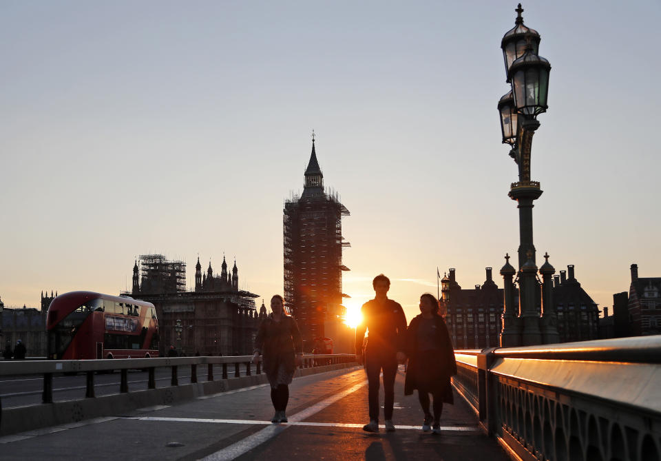 Pedestrians cross Westminster Bridge during sunset in London, Tuesday, March 23, 2021. One year since Prime Minister Boris Johnson announced UK-wide lockdown to slow the fast-spreading coronavirus, a national day of reflection is being organized to remember the people who died after contracting COVID-19. The U.K. has registered more than 126,000 virus-related deaths, the highest pandemic death toll in Europe and the fifth-highest worldwide.(AP Photo/Frank Augstein)