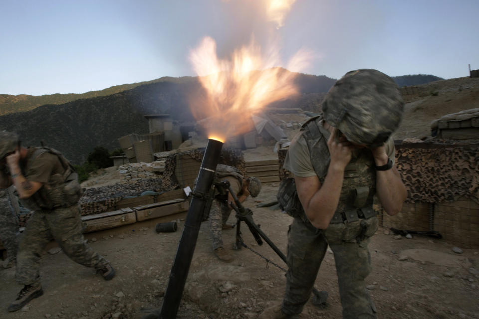 Soldiers from the U.S. Army First Battalion, 26th Infantry fire mortars from the Korengal Outpost at Taliban positions in the Korengal Valley of Afghanistan's Kunar Province on May 12, 2009. (AP Photo/David Guttenfelder, File)