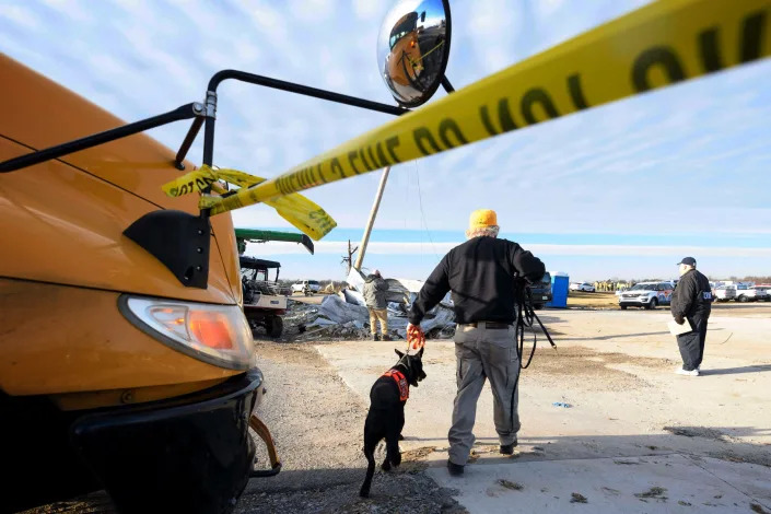 Image: A rescue worker and a cadaver dog arrive at the Mayfield Consumer Products candle factory in Mayfield, Ky., on Dec. 11, 2021. (John Amis / AFP via Getty Images)