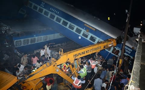 Emergency workers look for survivors on the wreckage of a train carriage the incident - Credit: AFP