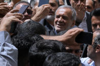 Reformist candidate for the Iran's presidential election Masoud Pezeshkian is greeted by his supporters as he arrives to vote at a polling station in Shahr-e-Qods near Tehran, Iran, Friday, July 5, 2024. Iranians are voting in a runoff election to replace the late President Ebrahim Raisi, who was killed in a May helicopter crash in the country’s northwest along with the foreign minister and several other officials. (AP Photo/Vahid Salemi)