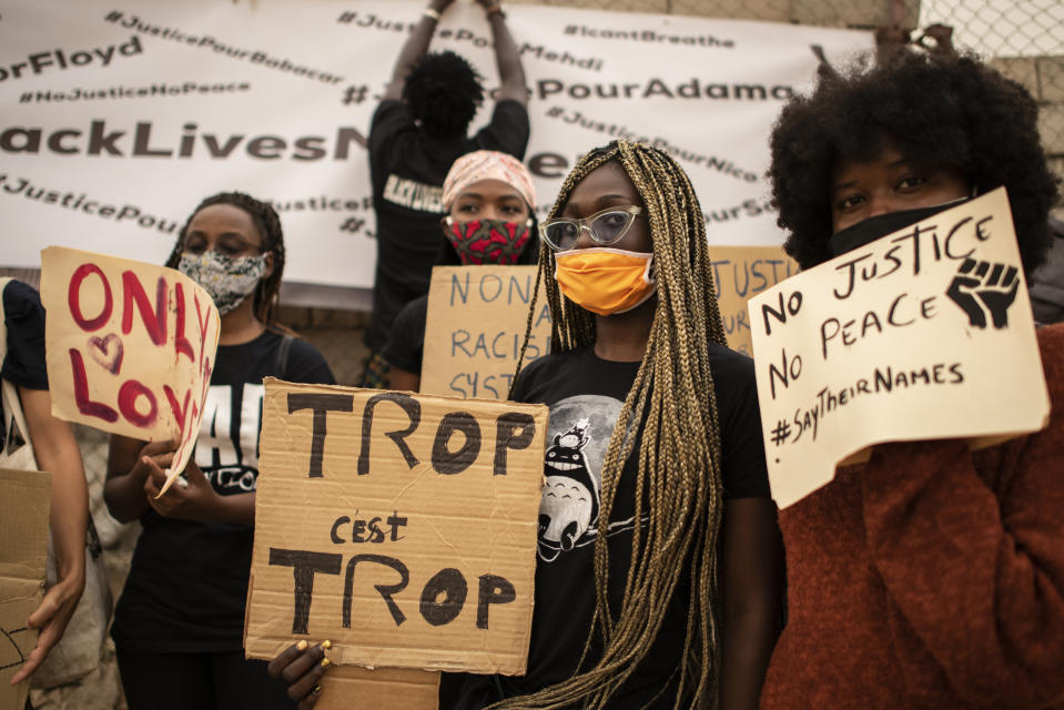 Protesters hold placards at a demonstration against the killing of George Floyd by police officers in Minneapolis, USA, held in front of the African Renaissance Monument in Dakar, Senegal Saturday, June 6, 2020. His death has led to Black Lives Matter protests in many countries and across the US. Placard in center in French reads "Too much is too much". (AP Photo/Sylvain Cherkaoui)