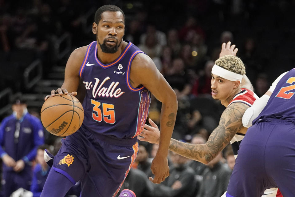 Phoenix Suns' Kevin Durant (35) dribbles around Washington Wizards' Kyle Kuzma during the first half of an NBA basketball game in Phoenix, Sunday, Dec. 17, 2023. (AP Photo/Darryl Webb)