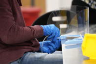 FILE - In this Dec. 3, 2020, file photo, a Gilero employee assembles a face shield in Pittsboro, N.C., as Gov. Roy Cooper tours the facility. States faced a deadline on Friday, Dec. 4, 2020, to place orders for the coronavirus vaccine as many reported record infections, hospitalizations and deaths, while hospitals were pushed to the breaking point — with the worst feared yet to come.(AP Photo/Gerry Broome, File)