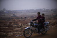 Displaced Syrians drive motorbikes next to refugee camps in Sarmada district, north of Idlib city, Syria, Friday, Nov. 26, 2021. In this opposition-held town near the border with Turkey, thousands of displaced Syrians go about their daily lives with little hope of returning home any time soon. (AP Photo/Francisco Seco)