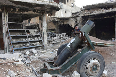 Syrian government soldiers walk near an abandoned weapon that belonged to rebels, after they took control of al-Sakhour neighborhood in Aleppo, Syria in this handout picture provided by SANA on November 28, 2016. SANA/Handout via REUTERS