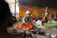 Hindu Holy men pray on the bank of the river Ganges during Magh mela festival, in Prayagraj, India. Tuesday, Feb. 16, 2021. Millions of people have joined a 45-day long Hindu bathing festival in this northern Indian city, where devotees take a holy dip at Sangam, the sacred confluence of the rivers Ganga, Yamuna and the mythical Saraswati. Here, they bathe on certain days considered to be auspicious in the belief that they be cleansed of all sins. (AP Photo/Rajesh Kumar Singh)