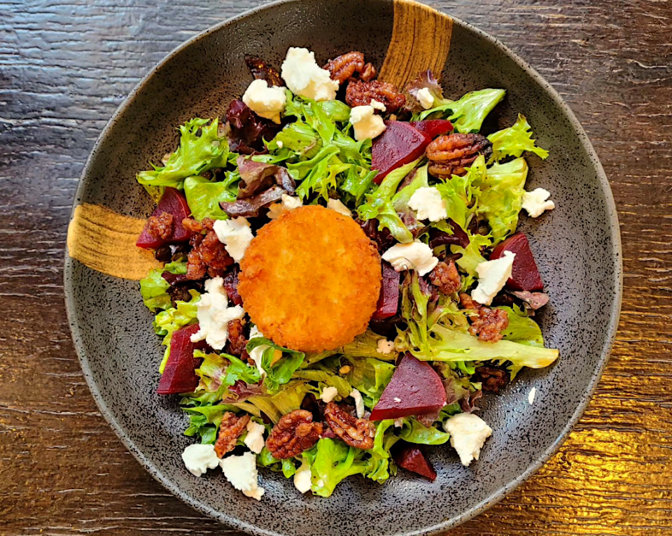 A goat cheese fritter sits on top of a salad at The Front Porch.